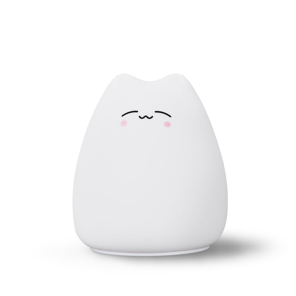 White cat-shaped lamp with a closed-eye face and pink cheeks on a white background